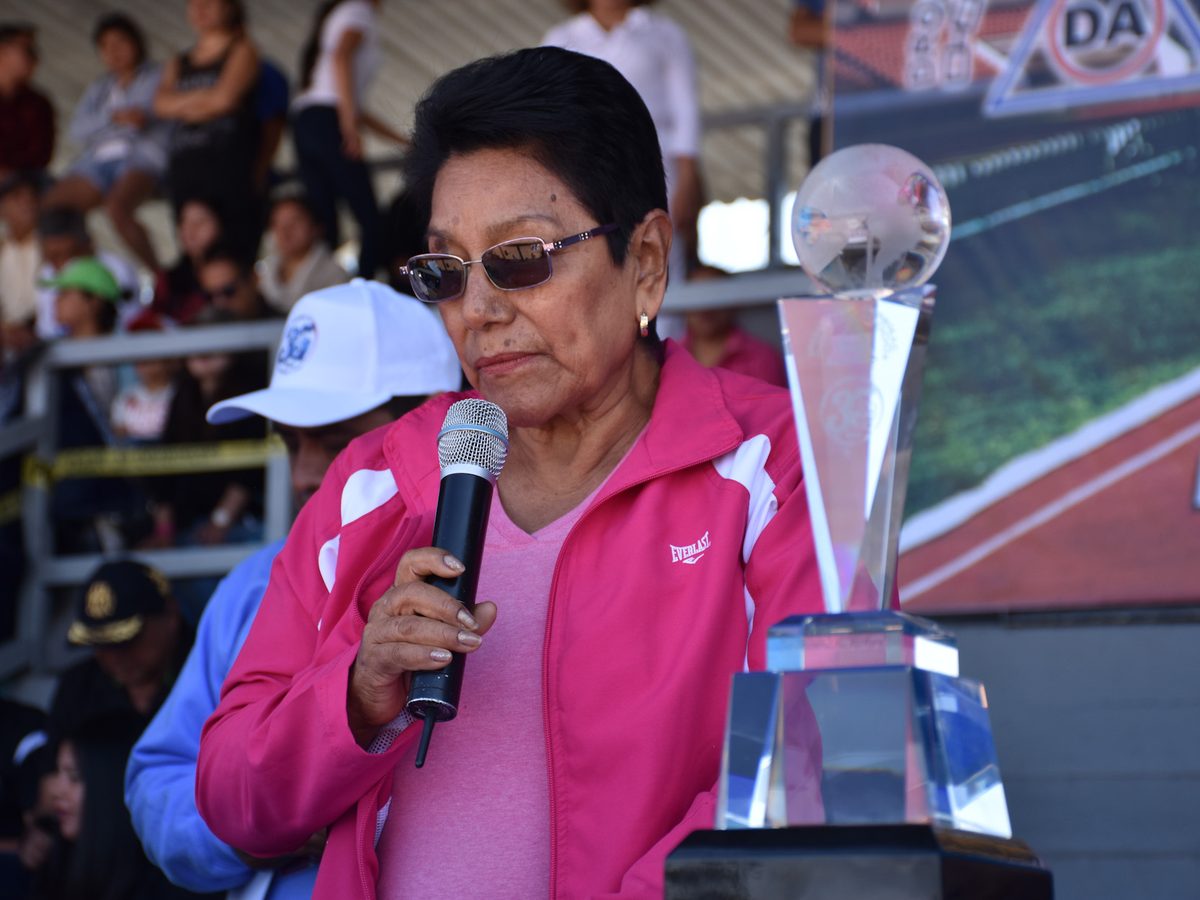 Oradora con micrófono junto al trofeo Paulita